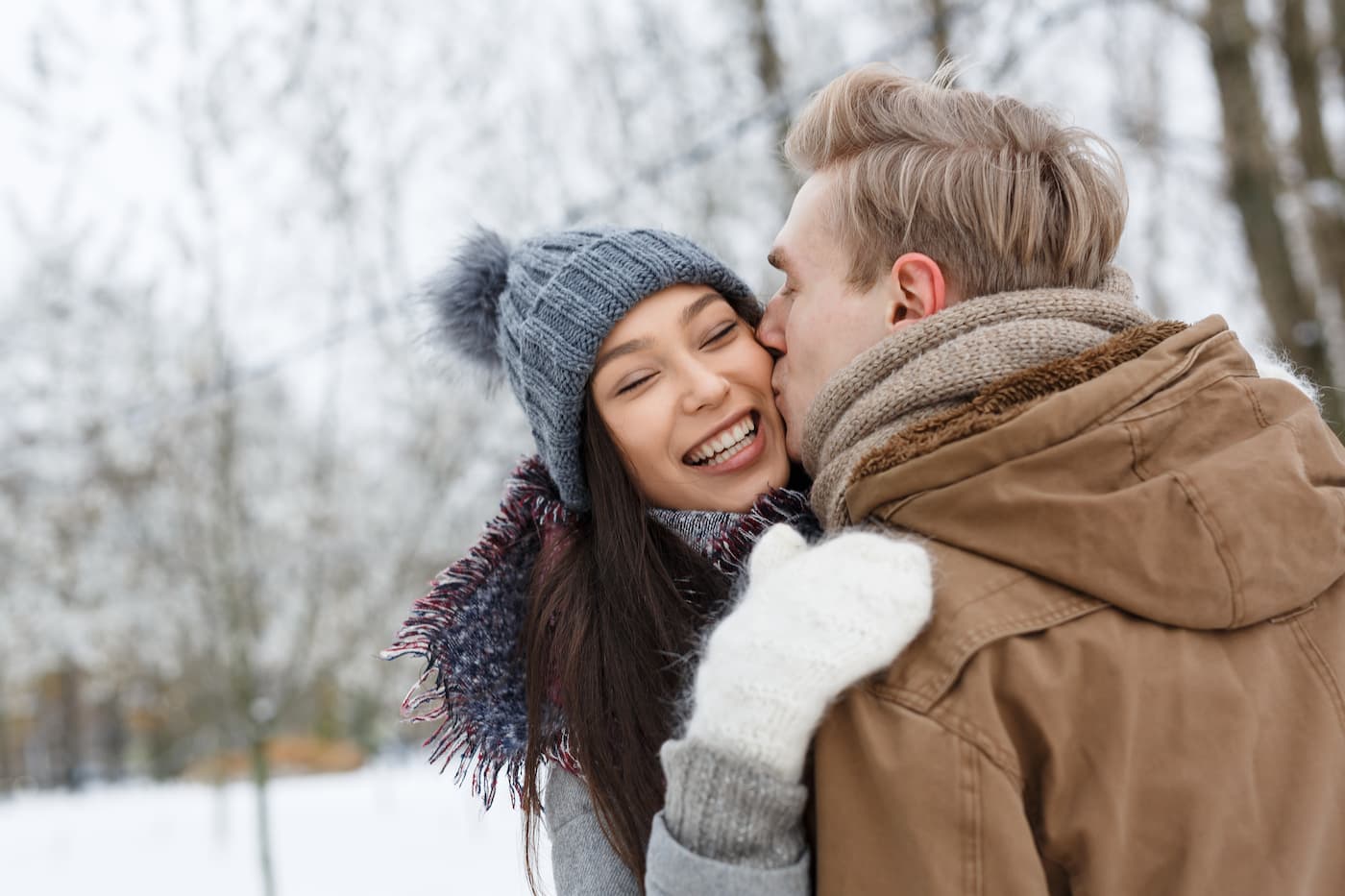 Man-kissing-woman-on-the-cheek-with-winter-background